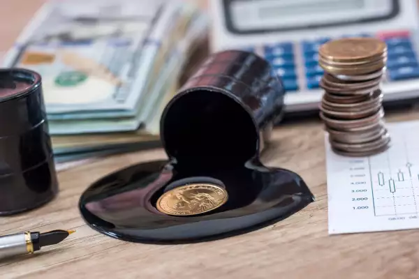 dollars banknote with spilled oil on desk. calculator with oil production schedule. business concept.