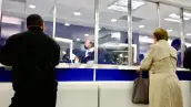 Personas reciben atención en ventanillas de un banco.