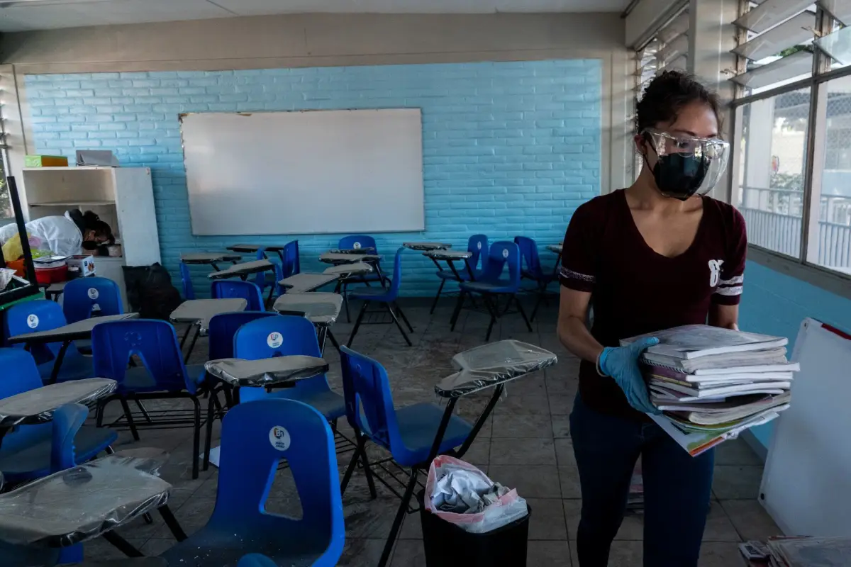 Mujer acomodando útiles en salón de escuela. En noviembre podría ser el regreso a clases presenciales en su totalidad. 
