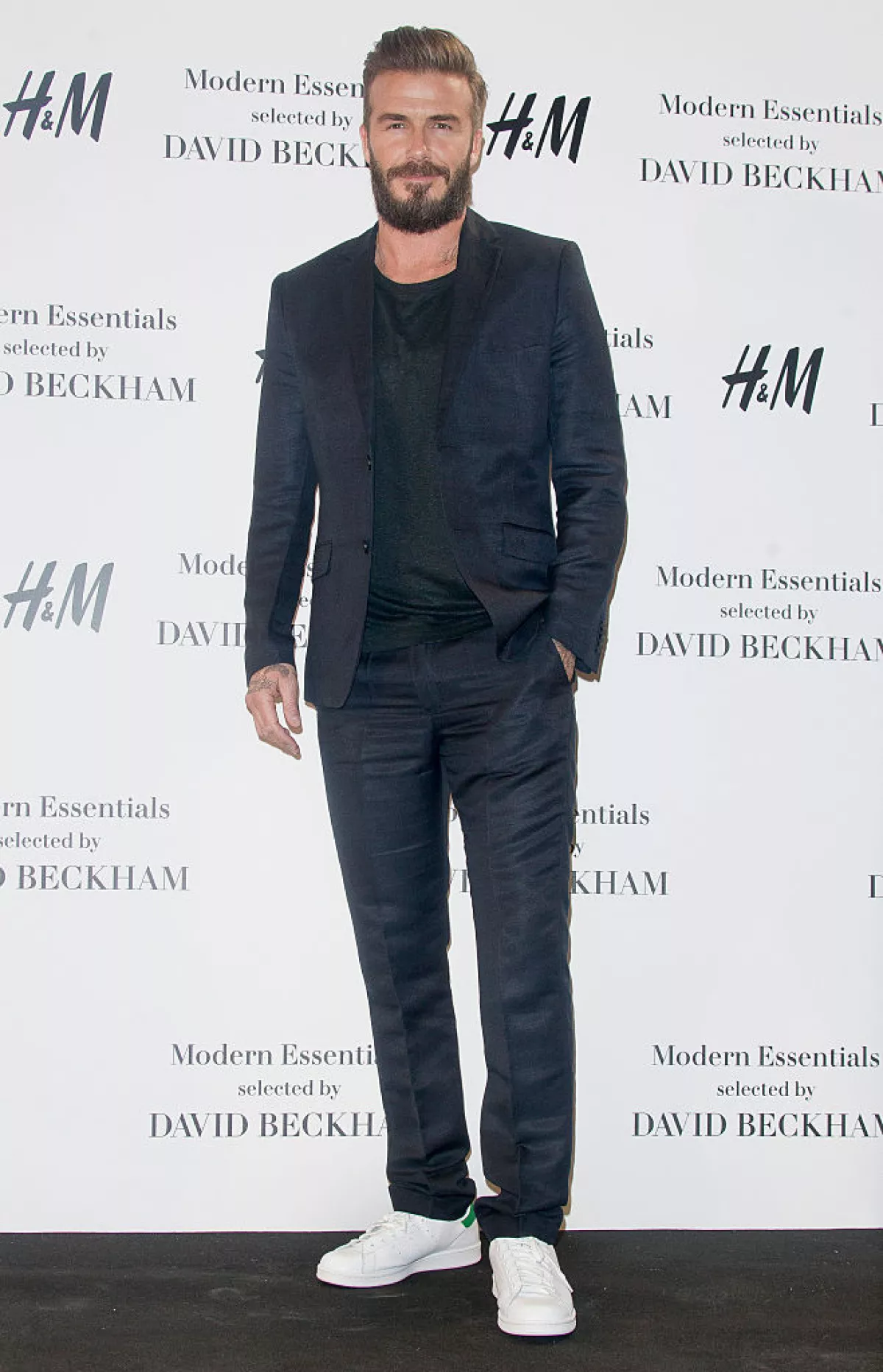 Foto de David Beckham con traje oscuro y tenis blancos en la presentación de su colección para H&M en 2015.