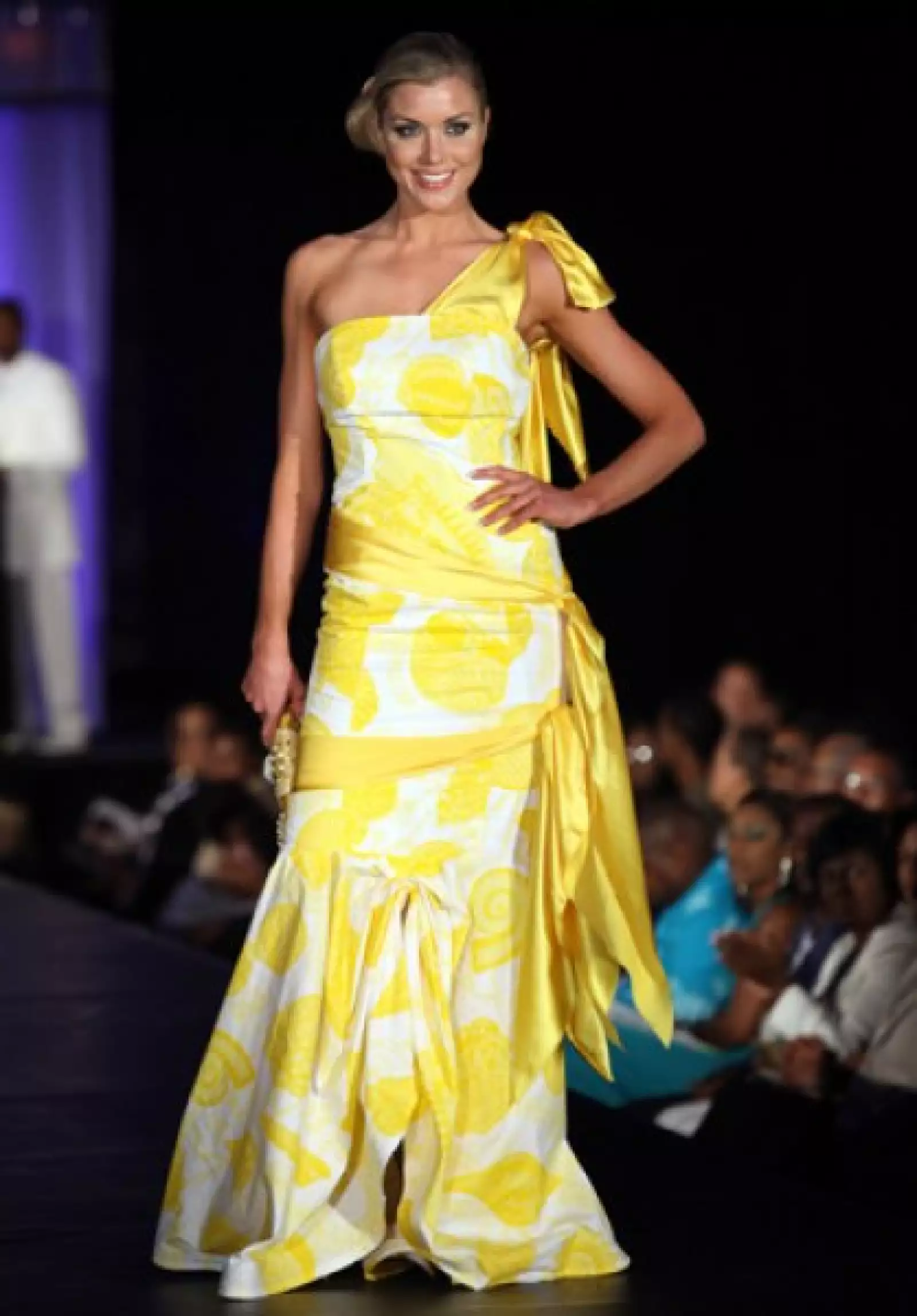 Ingibjorg Egilsdottir, de Islandia, en un vestido amarillo de un hombro y listones a tono en cintura y cadera.