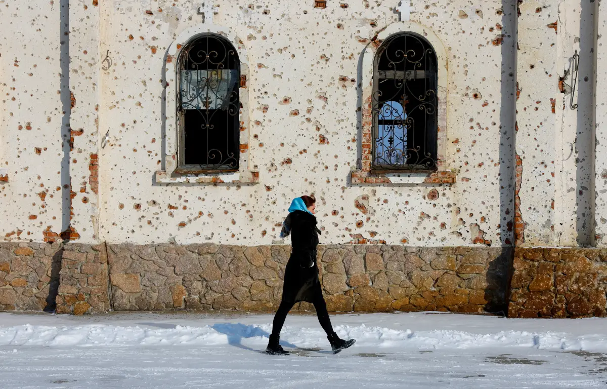 Una mujer camina fuera de St. El Convento de Iveron, que fue muy dañado por la artillería y los disparos durante las batallas por el aeropuerto local en el transcurso del conflicto ruso-ucrania, en Donetsk, una región controlada por Rusia de Ucrania, el 25 de febrero de 2025
