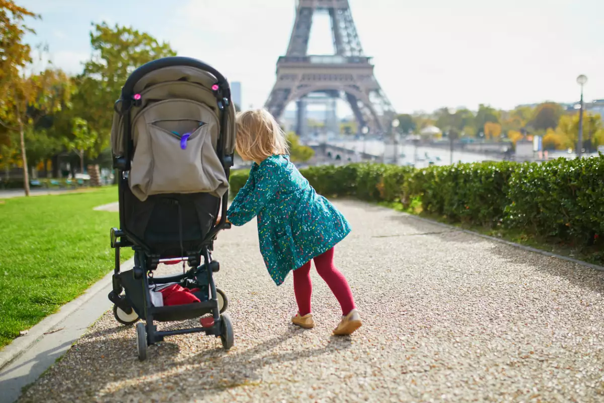 Adorable niña pequeña caminando cerca de la Torre Eiffel en París, Francia. Niño feliz disfrutando del día de otoño. Actividades de otoño al aire libre para niños