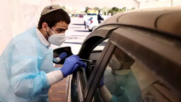 Personal médico lleva a cabo pruebas de detección del COVID-19 en un estacionamiento en Israel. 