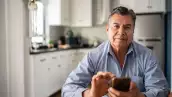 Portrait of mature man using mobile phone at home