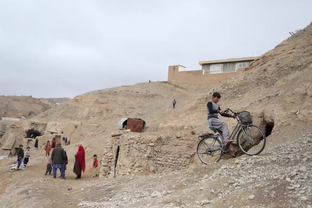 Un niño conduce una bicicleta cerca de unas casas en una colina en Bamiyan, Afganistán. 