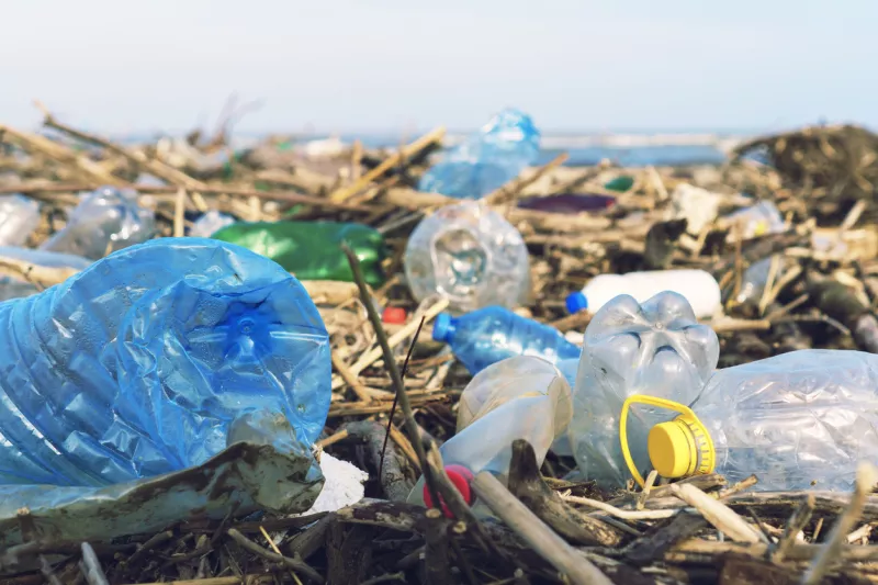 Spilled garbage on the beach of the big city. Empty used dirty plastic bottles. Dirty sea sandy shore of the Black Sea. Environmental pollution. Ecological problem