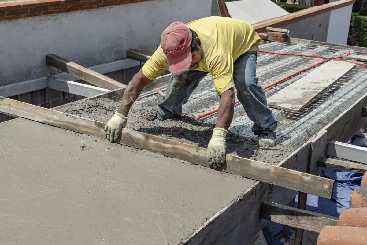 Worker levels a floor cement mortar.