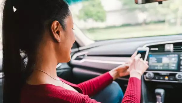 Woman using smartphone app on modern car. Mobile phone application, map navigation device technology, transportation, or crowdsourcing taxi concept