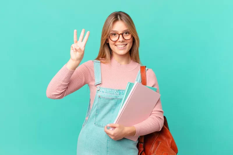 Young,Student,Woman,Smiling,And,Looking,Friendly,,Showing,Number,Three