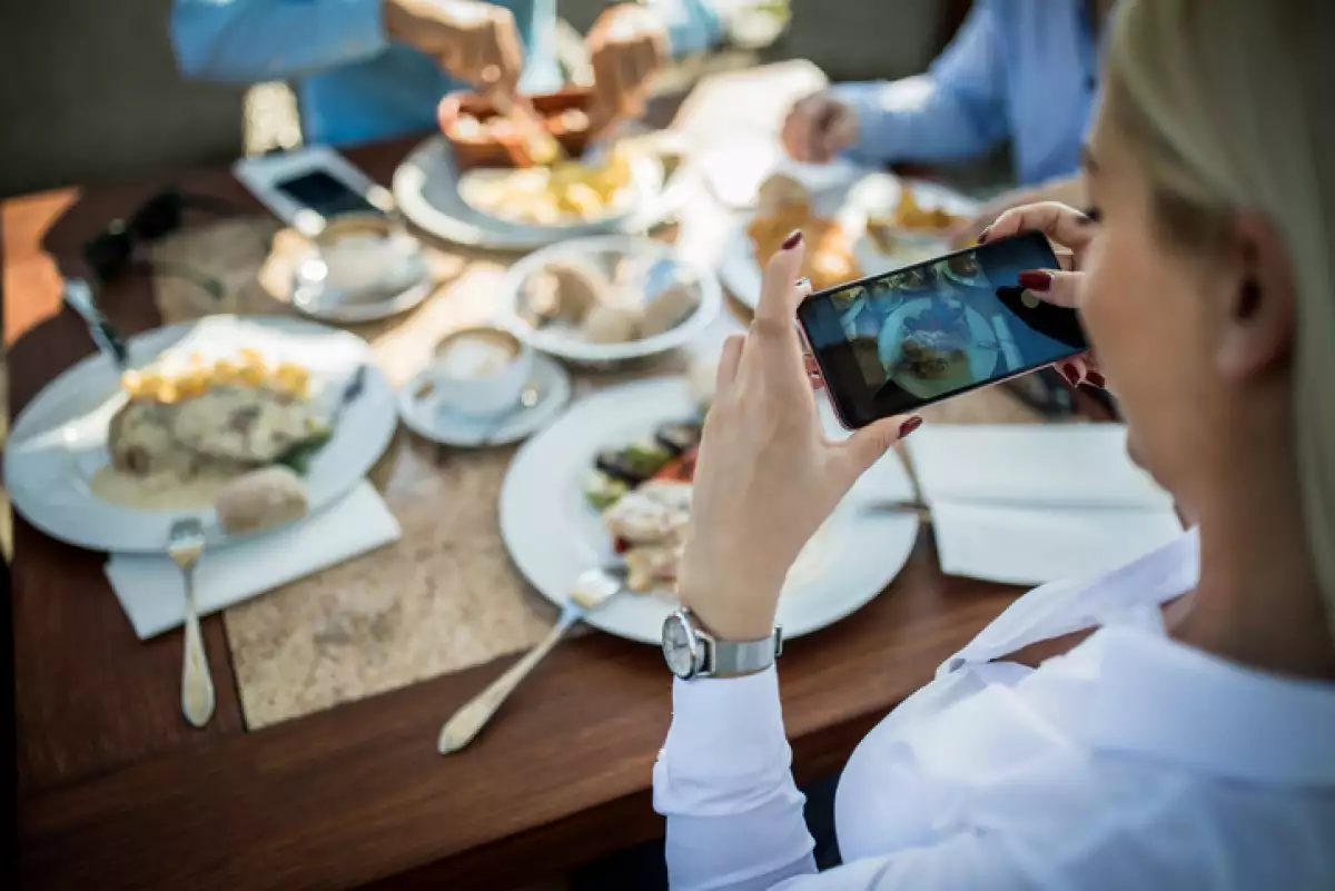 Mujer tomando foto a su platillo en restaurante.