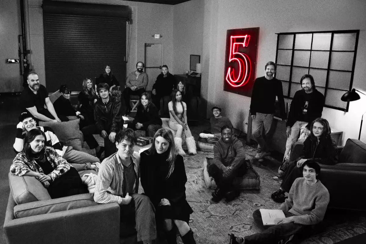 Foto en blanco y negro de todos los actores y actrices de Stranger Things juntos en una sala de lectura de guion junto a los hermanos Duffer.