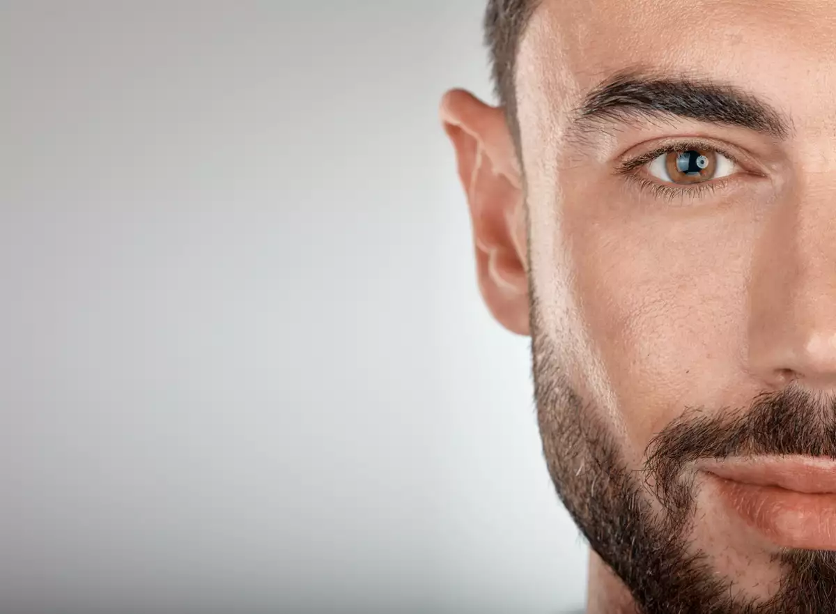 Foto de la mitad de la cara de un hombre con barba y piel limpia