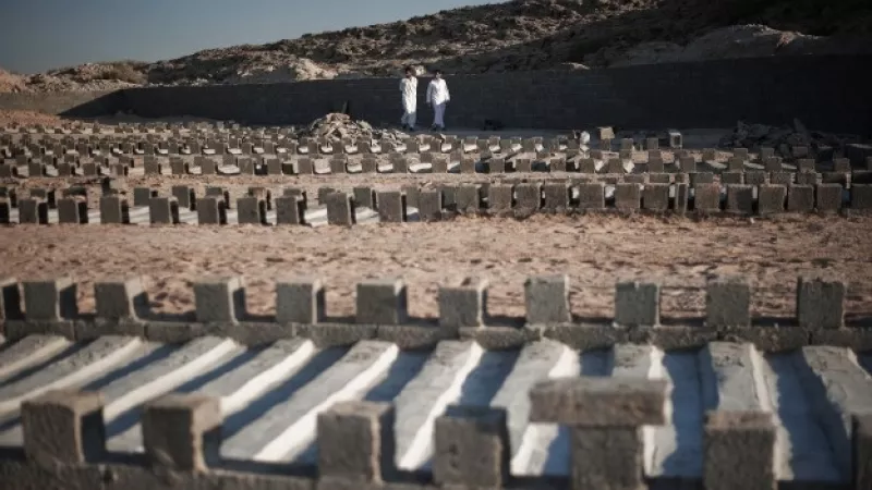 dos hombres caminana entre tumbas de solados fieles a gadhafi