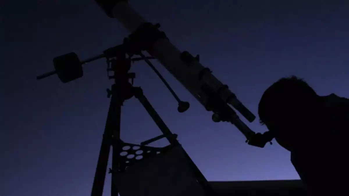 un hombre observa la luna a traves de un telescopio