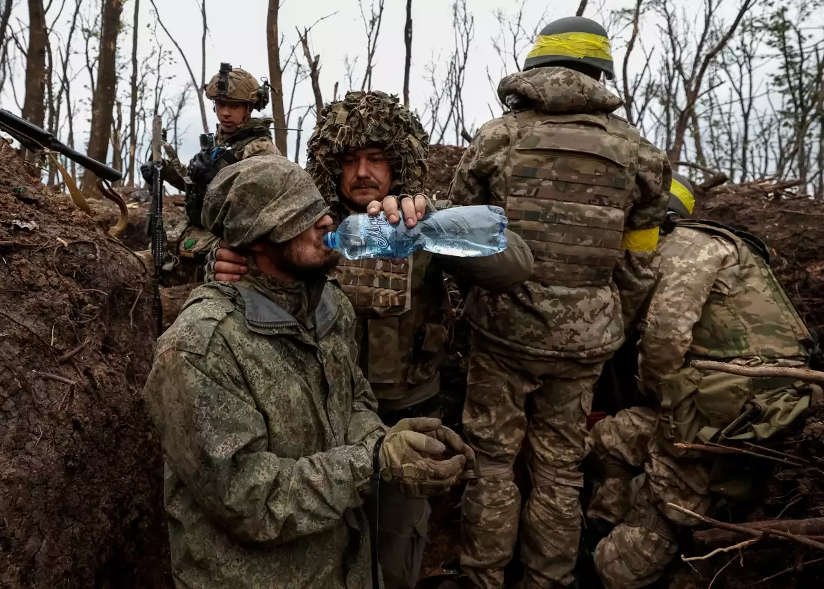 Un soldado ucraniano da agua a un militar del ejército ruso capturado, según ellos, en una posición recientemente ganada en la ofensiva, mientras continúa el ataque de Rusia a Ucrania, cerca de la ciudad de primera línea de Bajmut, en la región de Donetsk, Ucrania, el 11 de mayo de 2023.