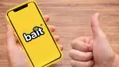 Una persona sosteniendo un teléfono con fondo amarillo y con el logo de Bait, el OMV de Walmart. 