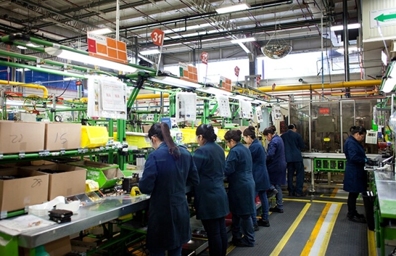 Vista de trabajadoras con los cuadernos de intrucciones del proceso, en la parte superior de su cabeza. Planta Schneider Electric