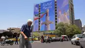Un hombre pasa junto a una pancarta gigante que representa misiles iraníes y una espada perteneciente al Imam Ali, el primer imán de los chiítas, en la plaza Vanak en Teherán el 10 de junio de 2026. El Ministerio de Relaciones Exteriores de Irán dijo el 10 de junio que Estados Unidos había dañado el esfuerzo diplomático internacional en curso para poner fin a la guerra, después de más ataques estadounidenses contra objetivos en el sur de Irán.