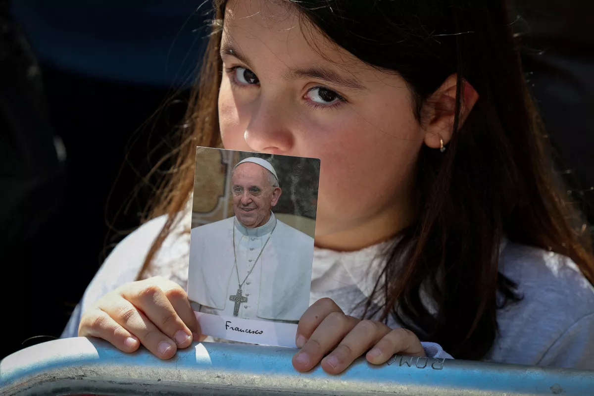 Una niña sostiene una foto del difunto Papa Francisco mientras espera la llegada de su ataúd fuera de la Basílica Papal de Santa María la Mayor, el día de su funeral, en Roma, Italia, el 26 de abril de 2025.