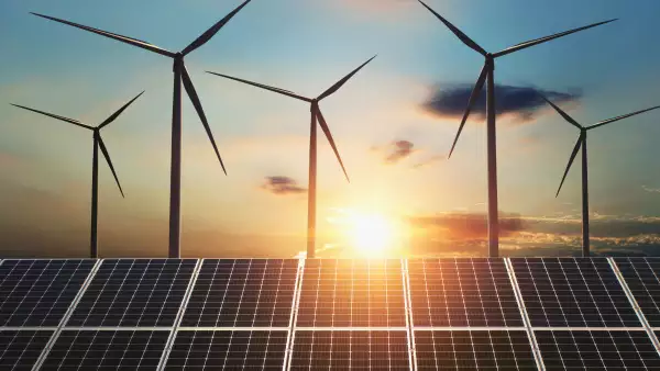 concept clean energy. wind turbine and solar panel in sunrise background