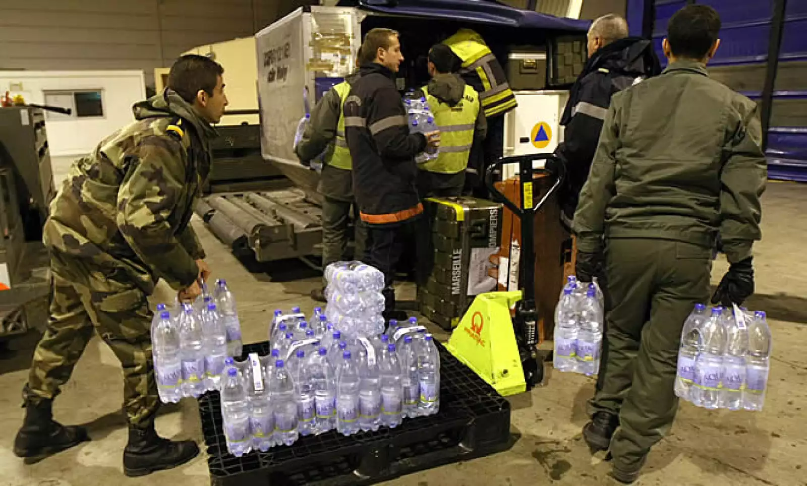 Miles de toneladas de comida, agua y medicamentos han empezado a llegar al aeropuerto de la ciudad de Puerto Principe. En la foto, bomberos franceses se alistan para ayudar descargando agua y otros alimentos.