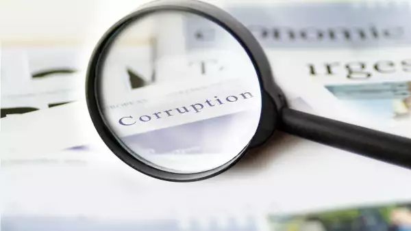 Corruption news concept showing a printed newspaper with a magnifying glass