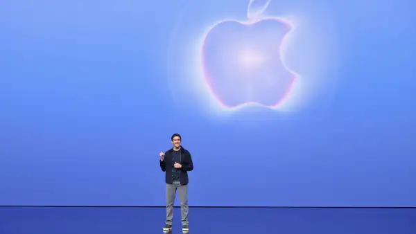 Imagen de John Ternus, nuevo CEO de Apple, en el escenario con el logo de su empresa détras en un estilo transparente.