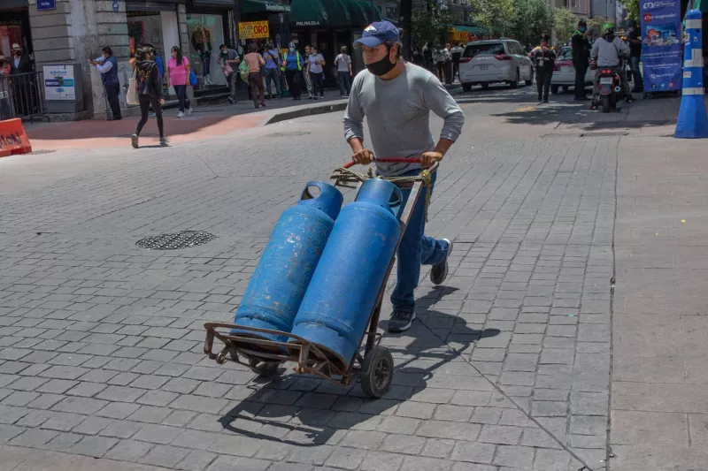 Un hombre transporta dos tanques de gas.