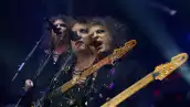 Foto de Robert Smith cantando y tocando la guitarra durante un concierto de The Cure.