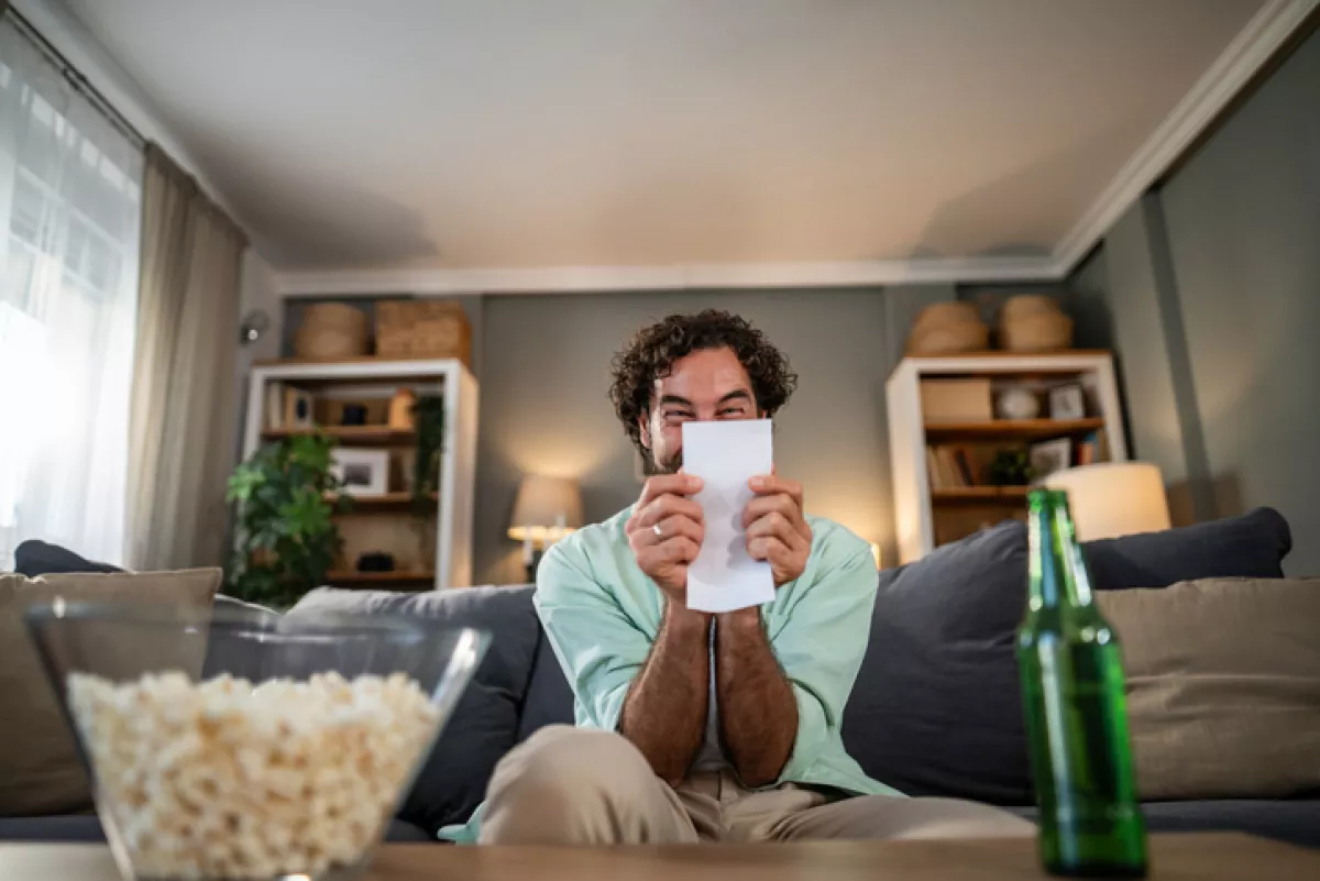 Man excitedly checking betting slip in living room