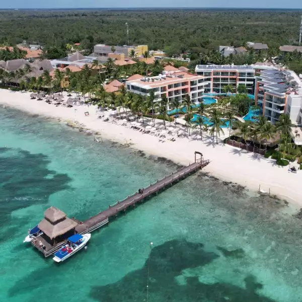 Foto del hotel Secrets Aura frente a la costa de Cozumel con el agua del mar color turquesa y la arena blanca.