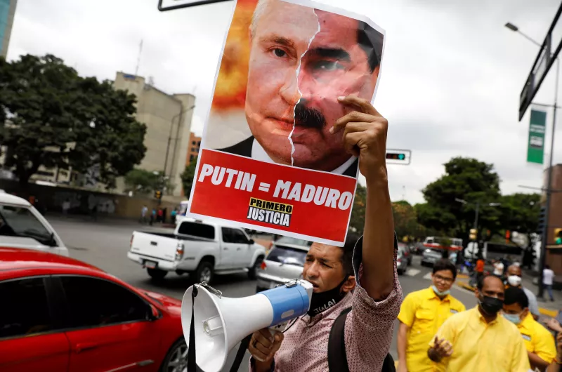 Un manifestante en Caracas, Venezuela sostiene un cartel con un collage de fotos del presidente de Rusia, Vladimir Putin, y el presidente de Venezuela, Nicolás Maduro.