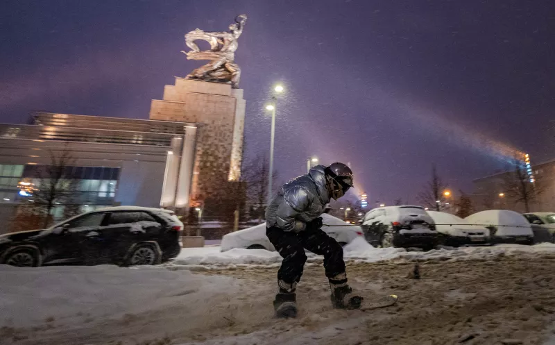 Un snowboarder está siendo tirado por un coche cerca de la escultura "Worker and Kolkhoz Woman" durante una fuerte nevada en Moscú, Rusia, el 3 de diciembre de 2023.