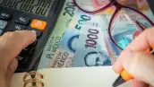 Un empresario hace la estimación del pago de sus impuestos con calculadora, pluma y libreta en mano. 
