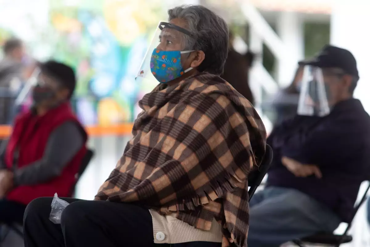 Una señora adulta mayor esperando en una silla.