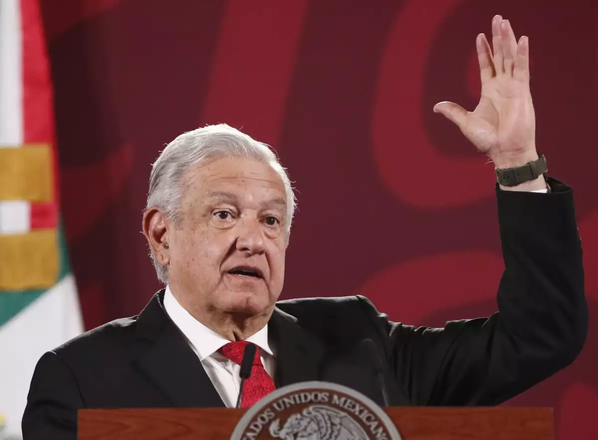 AMLO en su conferencia mañanera levanta la mano izquierda mientras habla de los hechos violentos de Querétaro.