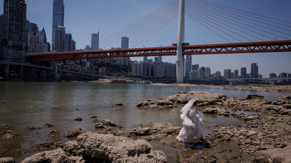 Una mujer con un vestido de novia camina sobre el lecho seco del río Jialing, un afluente del Yangtze, que se acerca a niveles de agua récord en Chongqing, China.