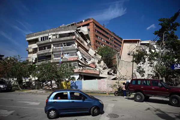Un automóvil conduce frente a edificios derrumbados después de un terremoto en Catia La Mar, estado de La Guaira, a unos 30 km al noroeste de Caracas, el 25 de junio de 2026.