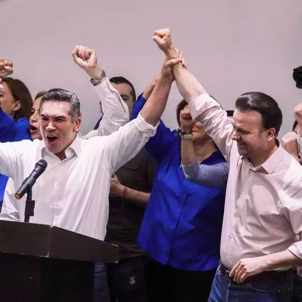 Alejandro Moreno Cárdenas alza el brazo de Esteban Villegas durante la conferencia de prensa en que declararon su triunfo en Durango de acuerdo a las encuestas de salida
