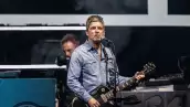 Foto de Noel Gallagher tocando la guitarra durante el primer concierto de Oasis en Cardiff.