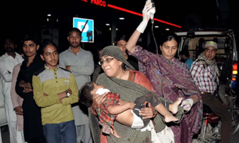 Una mujer traslada en brazos a su hijo, mientras otra sostiene la vía con suero, en espera de que atiendan a las víctimas del atentado (Foto: AFP)