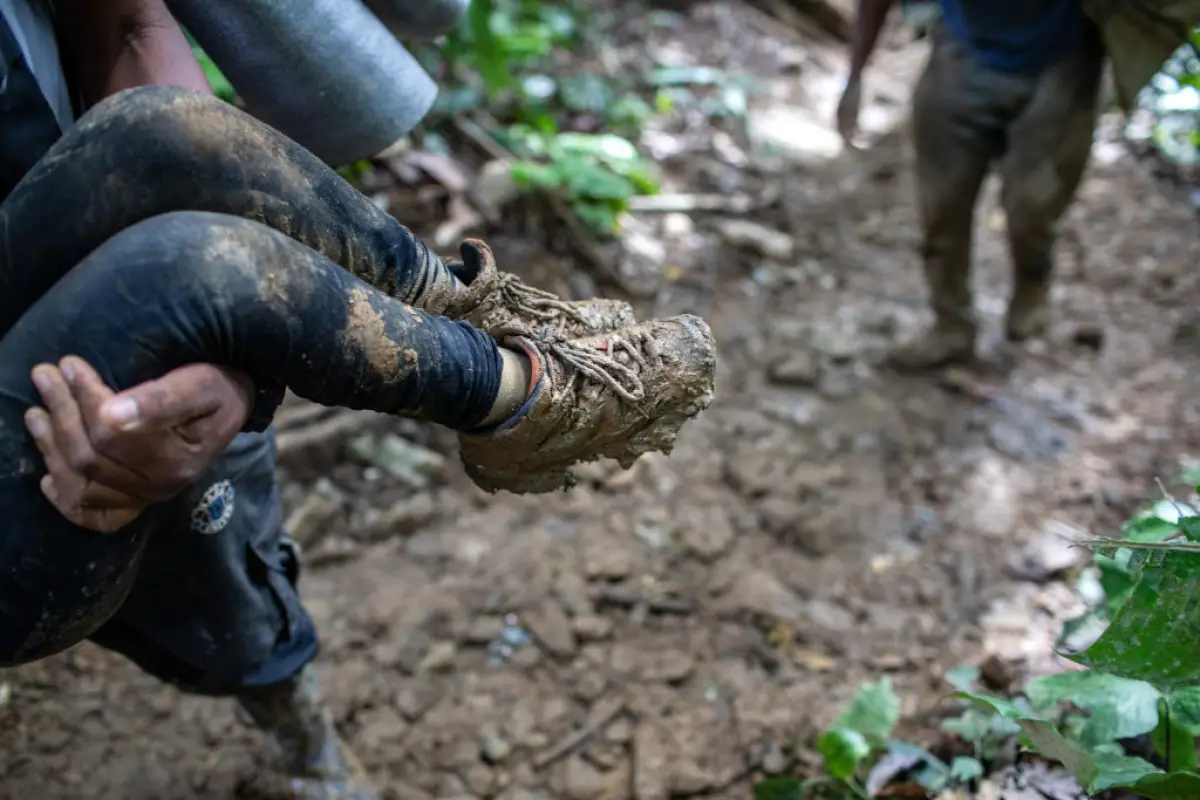 Un guía colombiano lleva a un niño haitiano por una ladera de una montaña cerca de la frontera de Colombia con Panamá el 19 de octubre de 2021 en Darien Gap, Colombia. La caminata de 66 millas a través de la densa selva tropical y las montañas se considera el tramo más difícil para los migrantes que viajan de América del Sur a los Estados Unidos.
