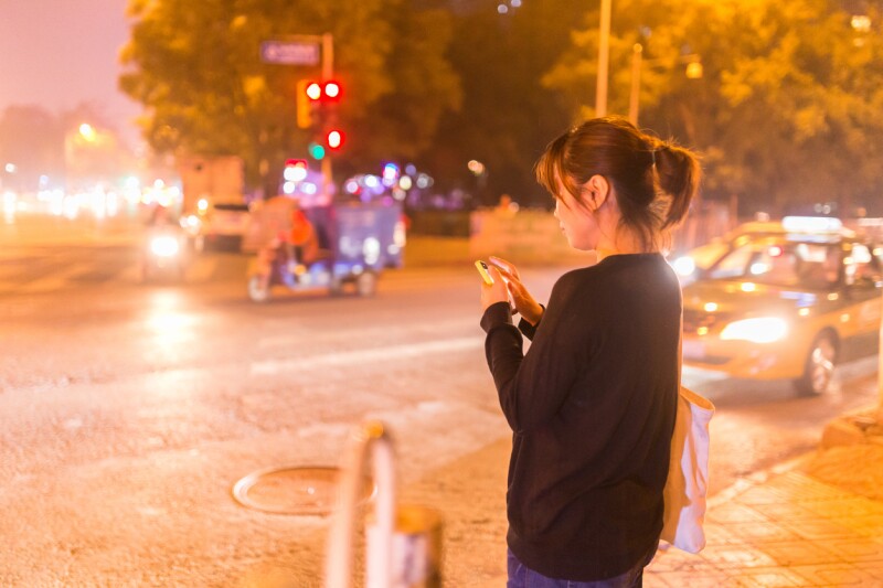 girl ordering taxi through phone at night