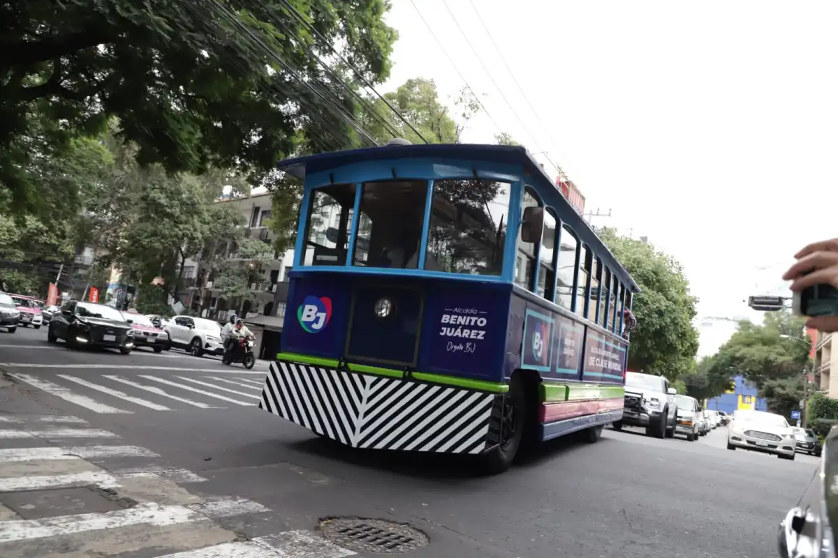 Una tranvía en color azul con vivos blancos en una calle de la CDMX en donde hay árboles al lado.jpg