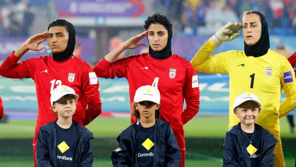 Los jugadores iraníes, la portera Raha Yazdani (R), Melika Motevalli (C) y Fatemeh Amineh, saludan durante el himno nacional antes del partido de fútbol de la Copa Asiática Femenina de la AFC Australia 2026 entre Irán y Filipinas en Gold Coast el 8 de marzo de 2026.