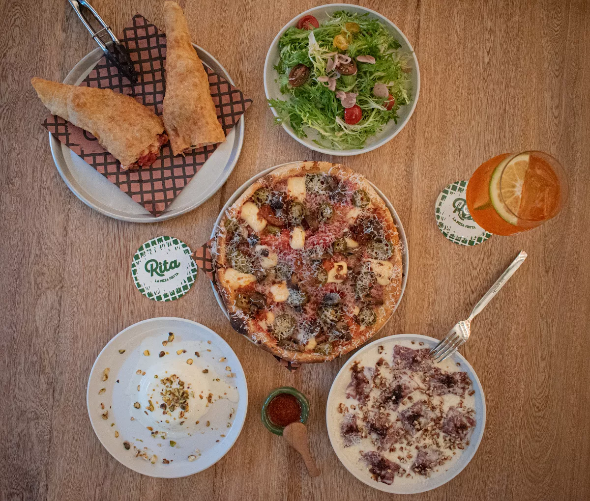 Foto de una mesa vista desde arriba llena de los platillos que se ofrecen en Rita La Pizza Frita.