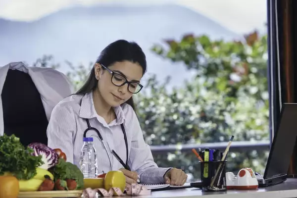 Nutrition dieting concept. Hispanic young nutritionist sitting at workplace with copy space