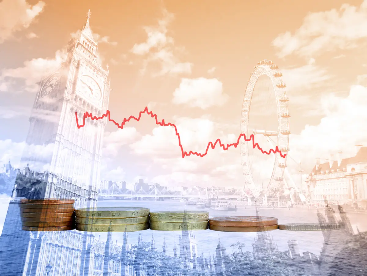 Piles of British coins with decreasing graph of UK currency