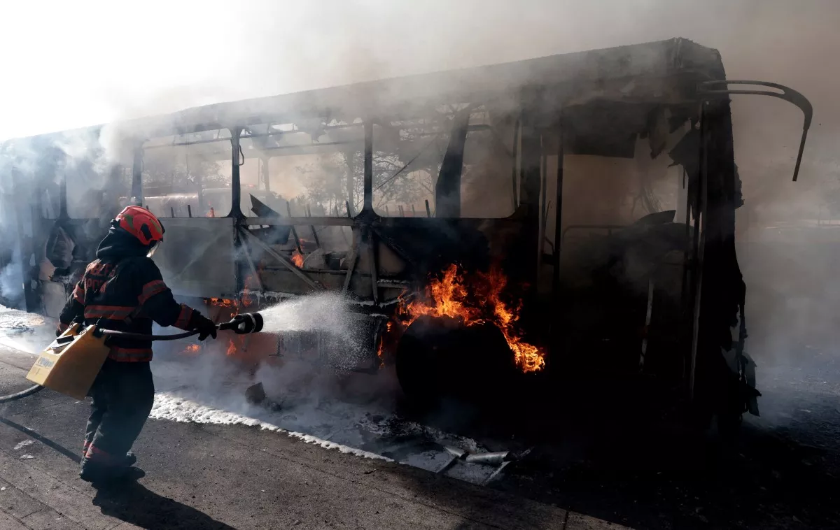 Un bombero apaga un autobús en llamas incendiado por grupos del crimen organizado en respuesta a una operación en Jalisco para detener a un objetivo de seguridad de alta prioridad, en una de las principales avenidas de Zapopan, estado de Jalisco, México, el 22 de febrero de 2026.